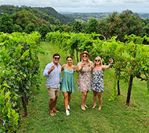 4 people in a vinyard with wine glasses
